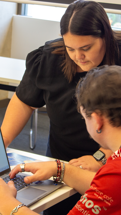 Emily, the Digital Skills Trainer, helping a participant find information in the workbook to put into the computer for an activity.